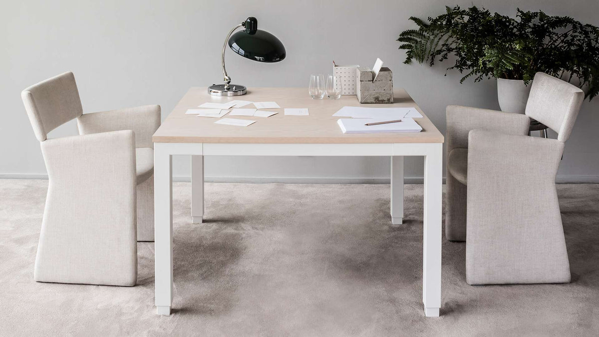 Kvadratiskt höj och sänkbart matbord med två stolar placerade mittemot varandra, skapar en intim och inbjudande atmosfär för måltider och samtal.