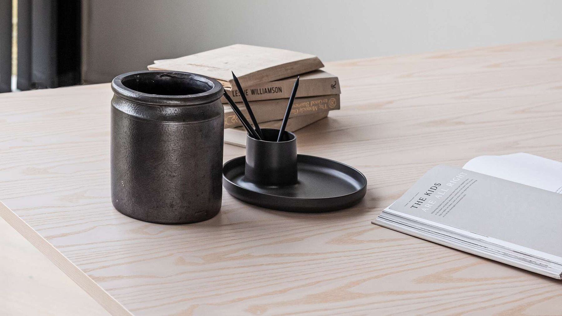 keramik kruka står på bordet tillsammans med ett bar böcker och ett pennställ med 4 pennor i.